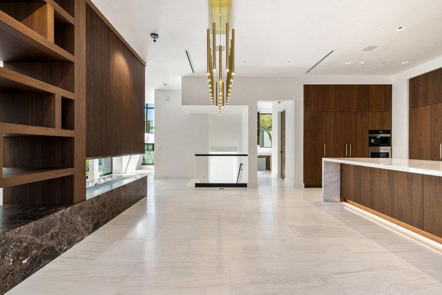 Kitchen with open floor plan, modern cabinets, dark brown cabinetry, light stone counters, and open shelves