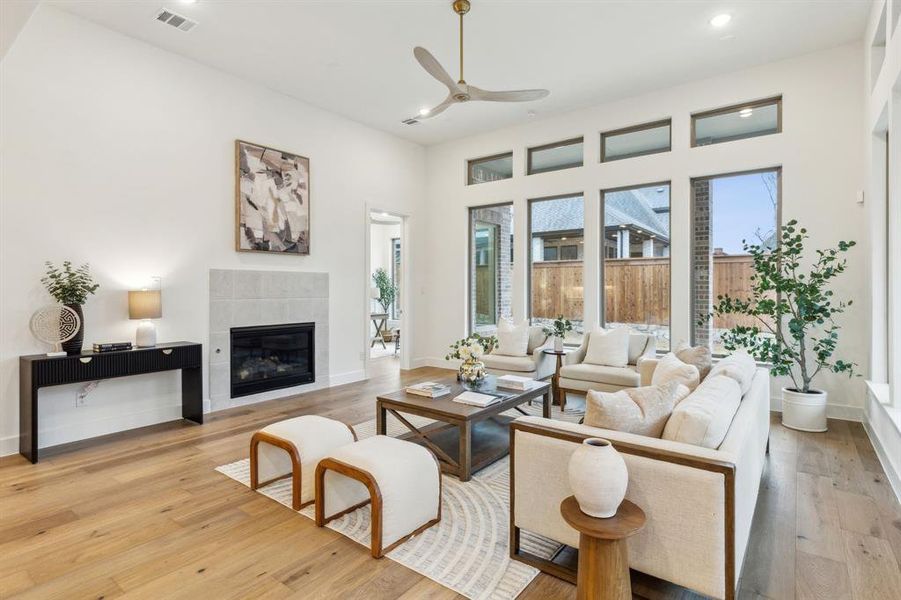 Living room with light hardwood / wood-style flooring, a tile fireplace, and ceiling fan