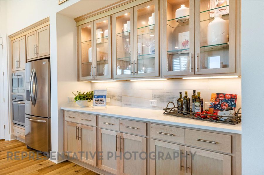 Bar with light brown cabinets, glass insert cabinets, tasteful backsplash, and stainless steel appliances Bar with light brown cabinets, glass insert cabinets, tasteful backsplash, and stainless steel appliances