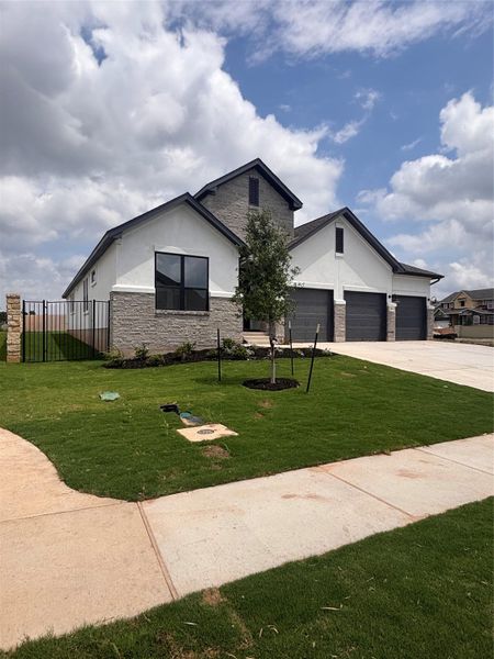 View of front of home featuring a front lawn, fence, stone siding, stucco siding, and concrete driveway View of front of home featuring a front lawn, fence, stone siding, stucco siding, and concrete driveway