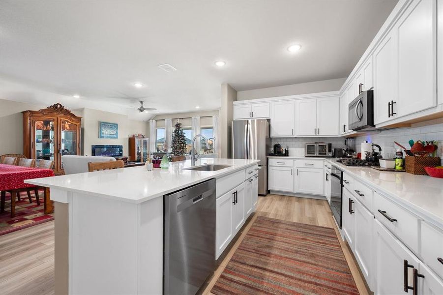Kitchen featuring appliances with stainless steel finishes, open floor plan, white cabinets, a center island with sink, and recessed lighting Kitchen featuring appliances with stainless steel finishes, open floor plan, white cabinets, a center island with sink, and recessed lighting