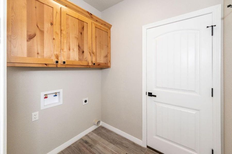 Clothes washing area featuring washer hookup, hardwood / wood-style flooring, cabinets, and hookup for an electric dryer