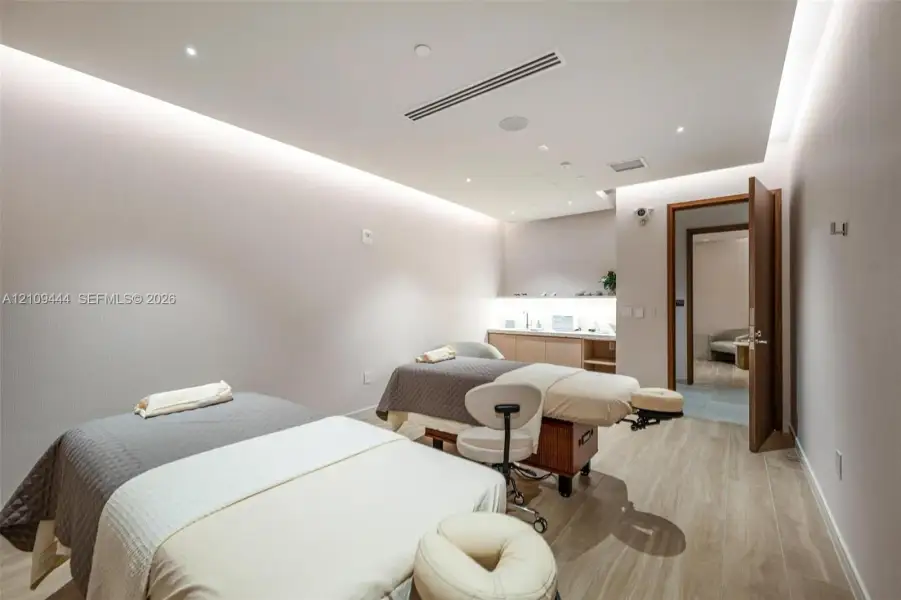 Interior room featuring wood-finish flooring, recessed ceiling lighting with perimeter cove illumination, and built-in cabinetry with integrated under-counter lighting
