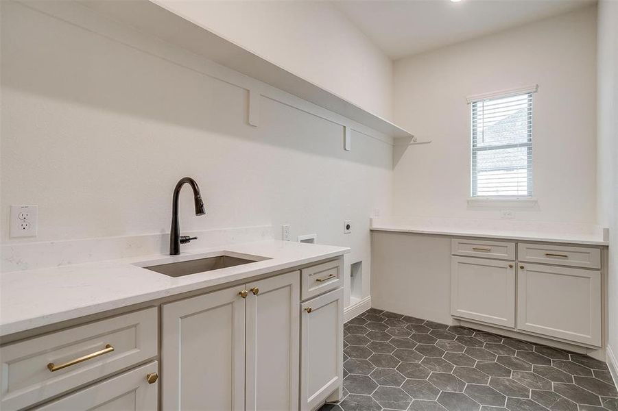 Laundry room featuring cabinets, washer hookup, electric dryer hookup, tile floor, and sink.