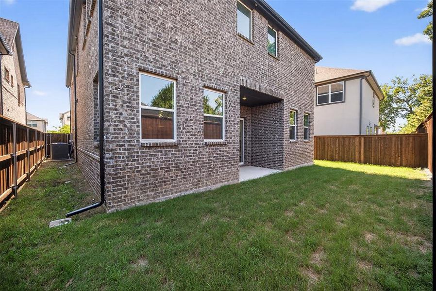 Back of house featuring a patio, a fenced backyard, and brick siding