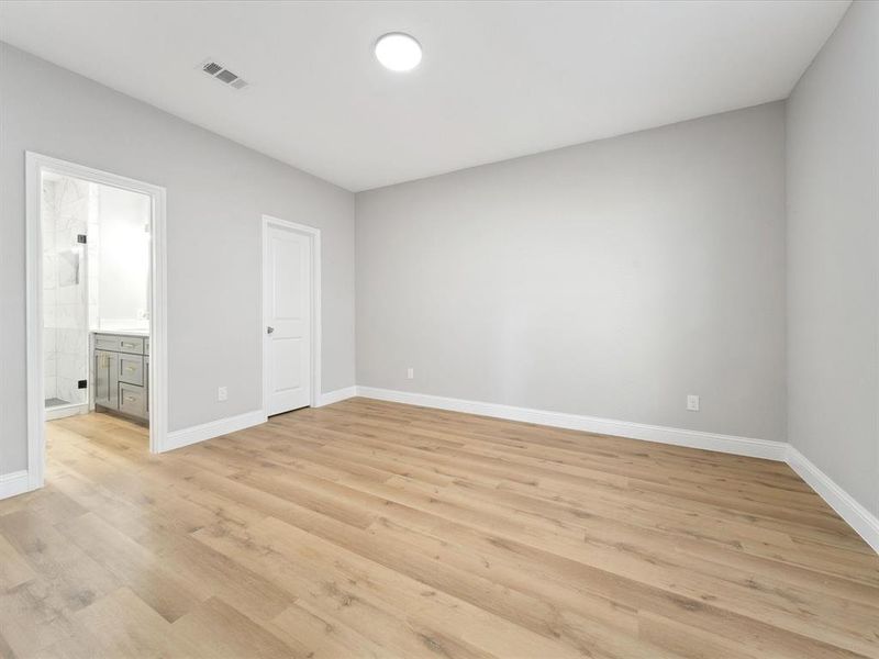 Unfurnished bedroom with connected bathroom and light hardwood / wood-style flooring