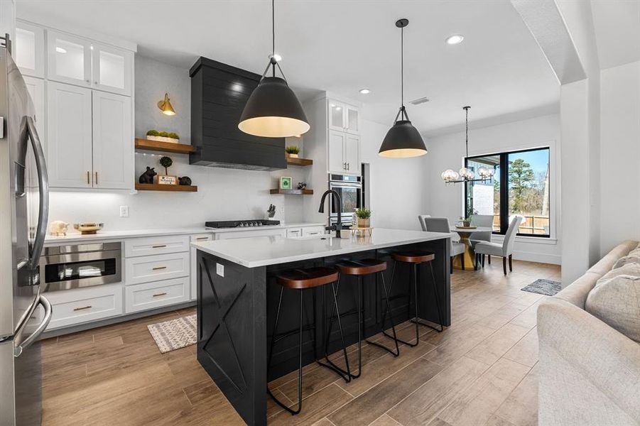 Kitchen featuring stainless steel appliances, light wood-style flooring, recessed lighting, open shelves, and light countertops Kitchen featuring stainless steel appliances, light wood-style flooring, recessed lighting, open shelves, and light countertops
