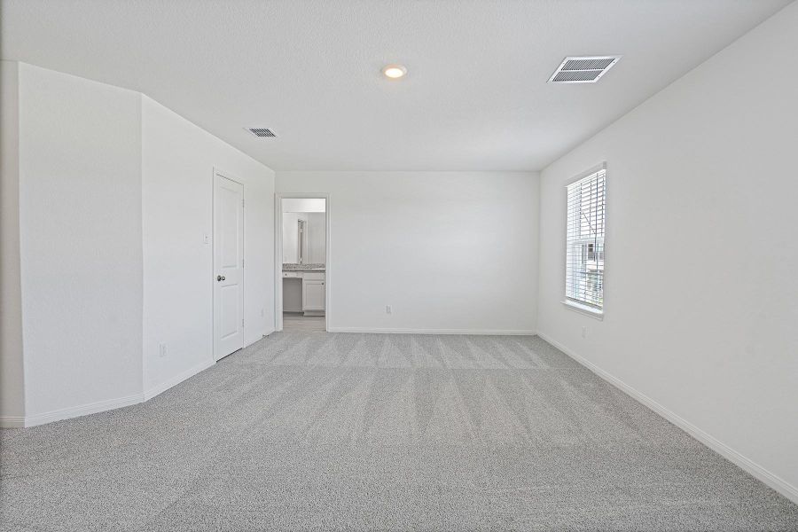 An airy bedroom with fresh carpeting and a window offering natural illumination.