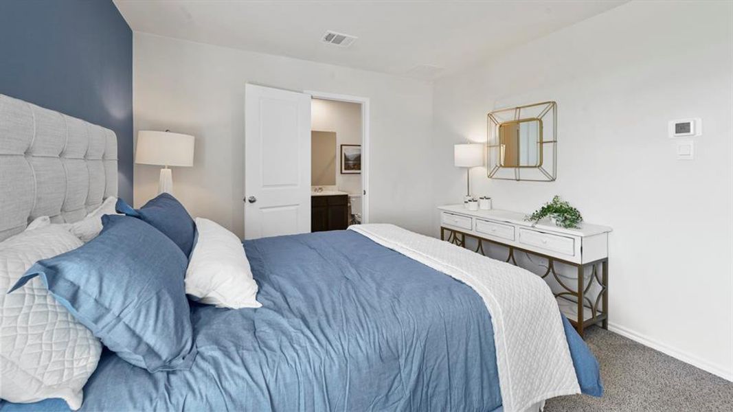 Bedroom featuring a tufted fabric headboard, accent wall, and carpet flooring