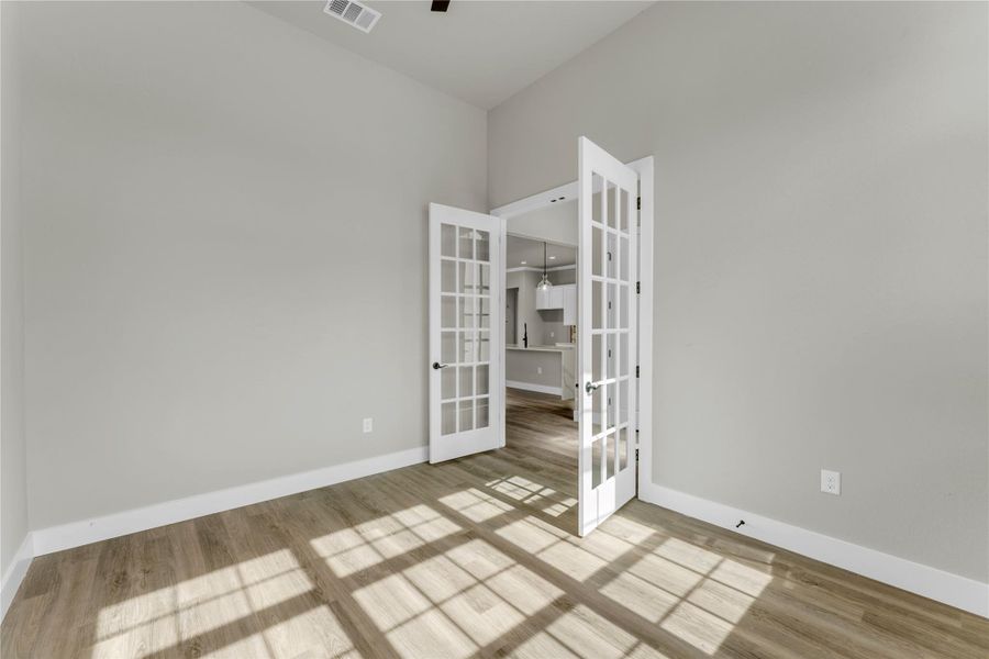 Unfurnished room with french doors, ceiling fan, and light wood-style flooring