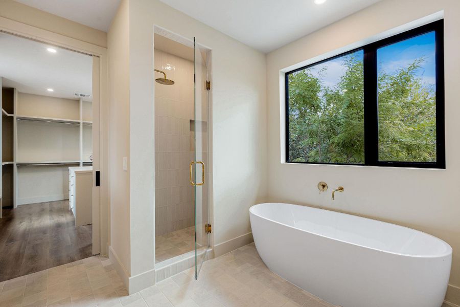 Full bath with a stall shower, a freestanding tub, a walk in closet, recessed lighting, and tile patterned floors Full bath with a stall shower, a freestanding tub, a walk in closet, recessed lighting, and tile patterned floors