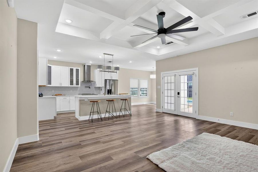 Open concept living room and kitchen over looking breakfast bar and outside back door patio, tray boxed ceilings, and designer lighting with high ceilings throughout the home, and wood looking luxury vinyl flooring.