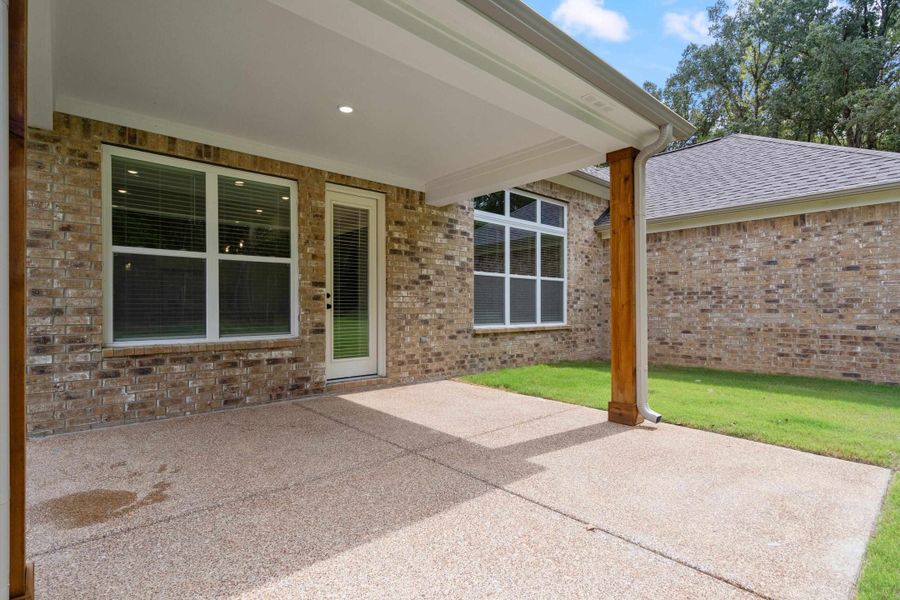 Covered patio with exposed aggregate concrete flooring, brick exterior, and recessed lighting Covered patio with exposed aggregate concrete flooring, brick exterior, and recessed lighting