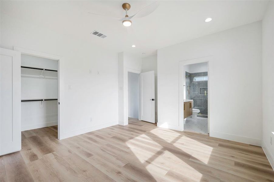 Unfurnished bedroom with a spacious closet, light wood-type flooring, connected bathroom, and a closet