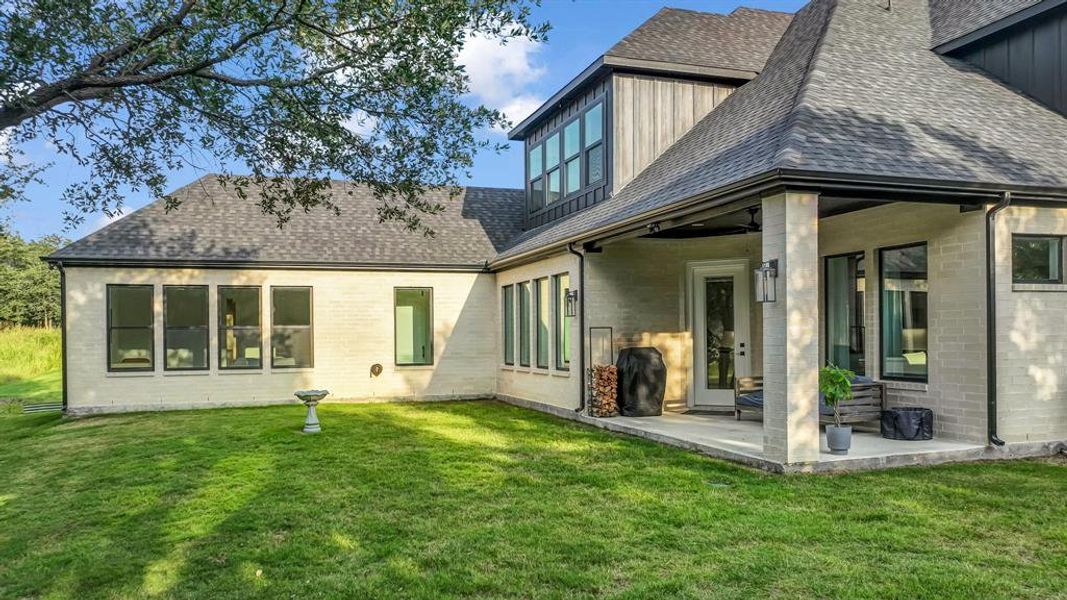Rear view of property with roof with shingles, a yard, and a patio area Rear view of property with roof with shingles, a yard, and a patio area