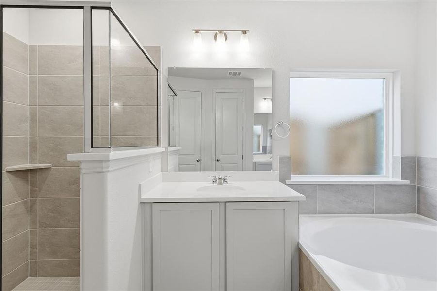Full bathroom featuring tiled shower, vanity, and a garden tub