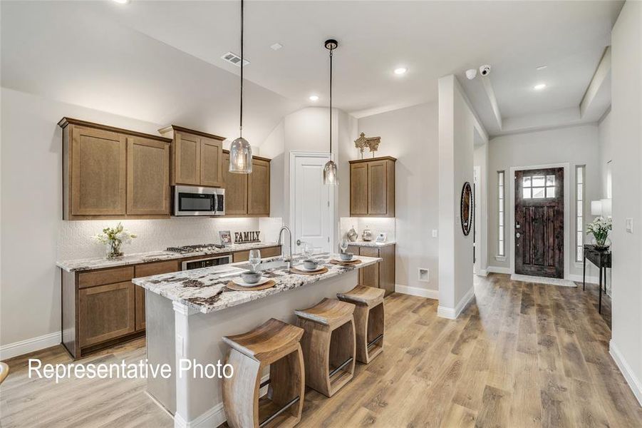 The kitchen features a spacious island with a light-colored countertop, wooden cabinetry, and stainless steel appliances