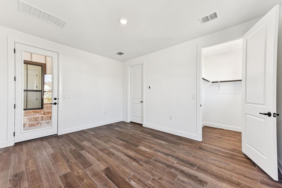 Unfurnished bedroom with a spacious closet, dark wood-style floors, and recessed lighting