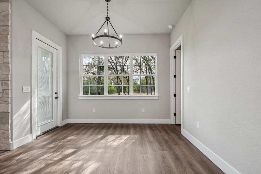 Unfurnished dining area featuring wood finished floors and a chandelier