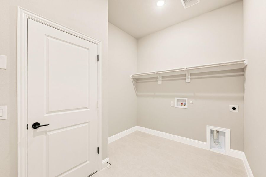 Laundry room with white wall shelf, washer and dryer hookups, and white panel door Laundry room with white wall shelf, washer and dryer hookups, and white panel door