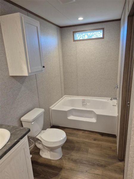 Full bath featuring a garden tub, vanity, and dark wood-style floors