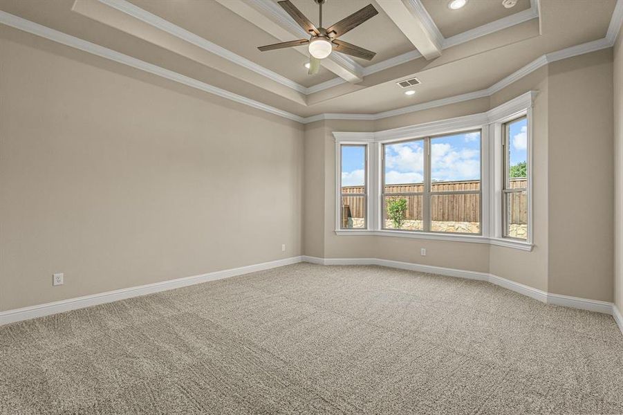 Carpeted spare room with ceiling fan, a raised ceiling, coffered ceiling, ornamental molding, and beam ceiling