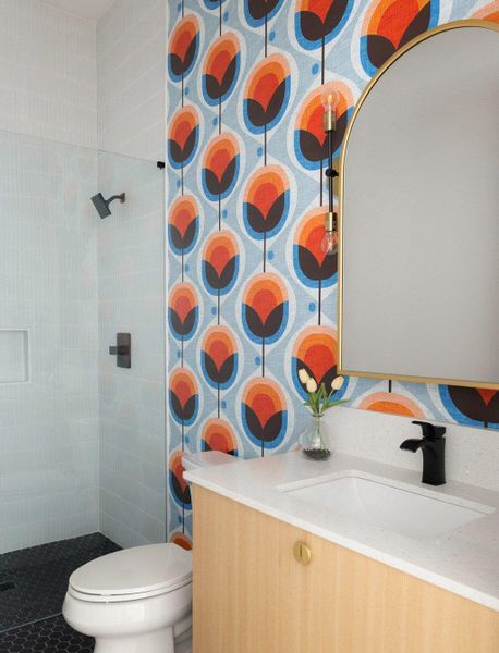Bathroom featuring wallpapered walls, vanity, and a tile shower