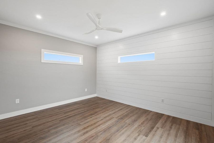 Unfurnished room with wood finished floors, ceiling fan, ornamental molding, recessed lighting, and wood walls