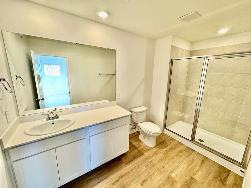 Bathroom featuring vanity, a stall shower, light wood-style flooring, and recessed lighting
