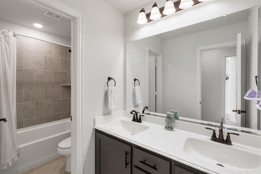 Full bathroom featuring shower / bath combination with curtain, vanity, and toilet