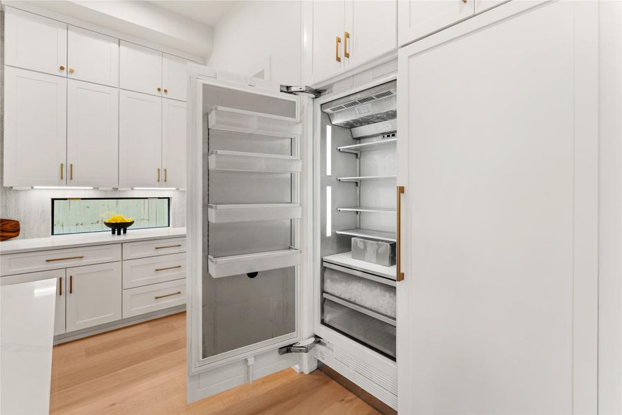 The gourmet kitchen includes a massive 60-inch Thermador built-in refrigerator/freezer featuring custom paneling that creates a cohesive look throughout the open kitchen.