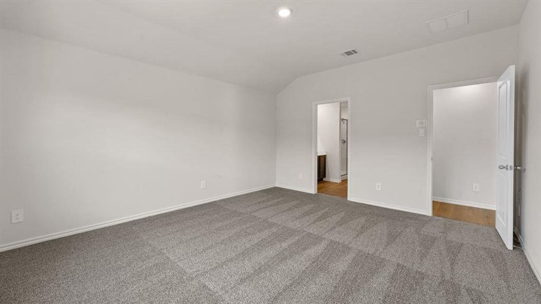 Spacious room featuring neutral tone walls, patterned gray carpet, and white trim