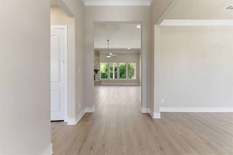 Spacious interior hallway featuring wood-finish flooring, light neutral wall tones, and white trim