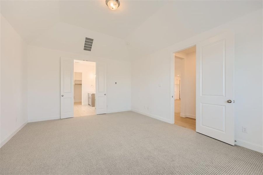 Unfurnished bedroom with a closet, connected bathroom, light carpet, and a spacious closet