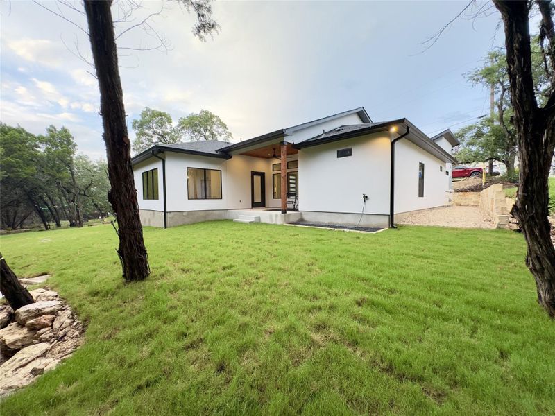 Rear view of house with stucco siding and a yard Rear view of house with stucco siding and a yard