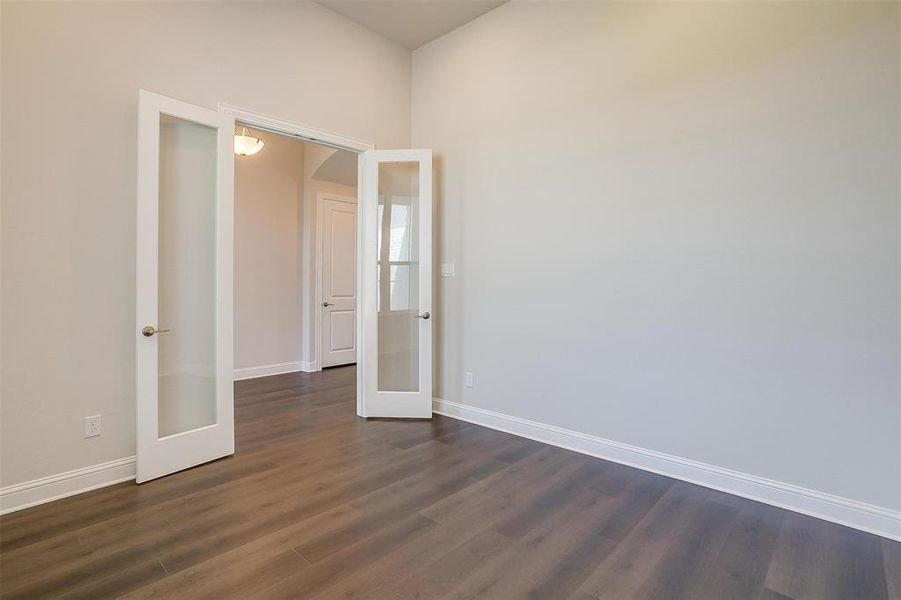 Unfurnished bedroom featuring french doors and dark hardwood / wood-style flooring