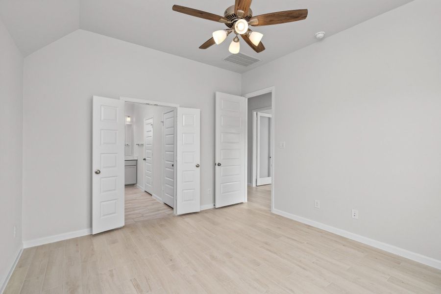 Primary bedroom suite with ceiling fan, wood-look tile flooring and private bath access.