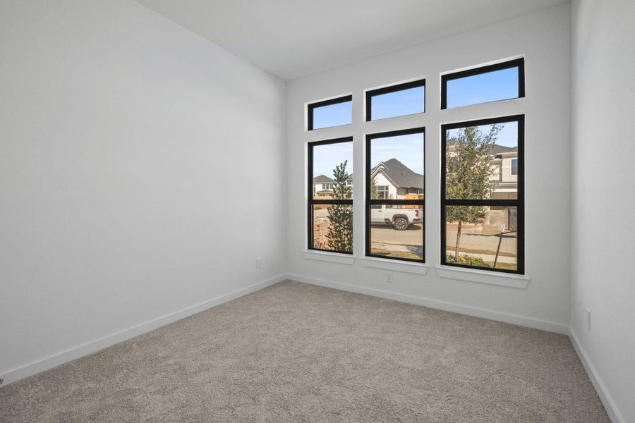 This downstairs secondary bedroom feels cozy and welcoming, featuring soft carpet underfoot that adds warmth and comfort. Large windows bring in natural light.