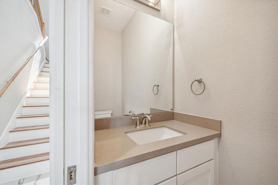 This photo showcases a half bathroom with a single vanity and a mirror. The space is practical, ideal for guest use or quick access from common areas.