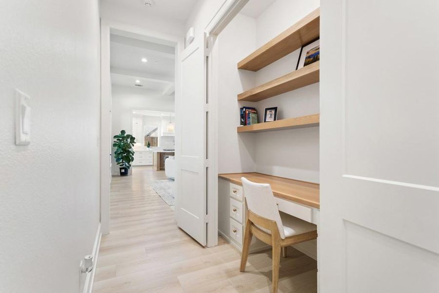 Office area with built in desk and light wood-style floors