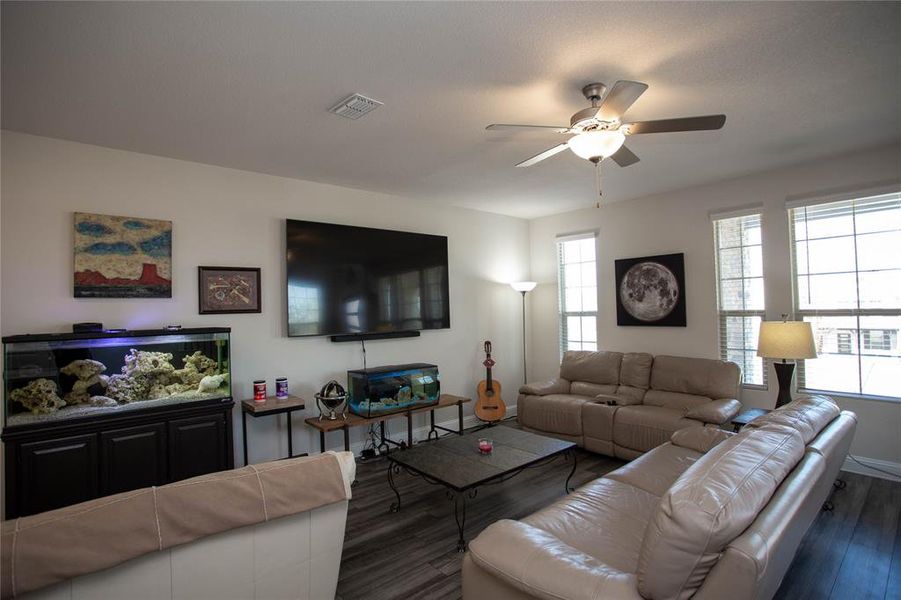 Living room with wood finished floors, a ceiling fan, visible vents, and baseboards