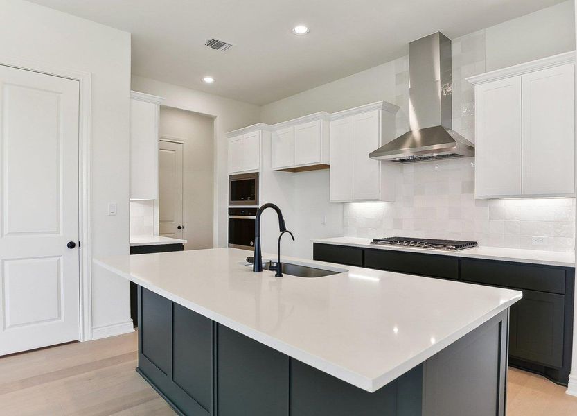 Kitchen featuring wall chimney range hood, white cabinets, light wood-type flooring, and a sink Kitchen featuring wall chimney range hood, white cabinets, light wood-type flooring, and a sink