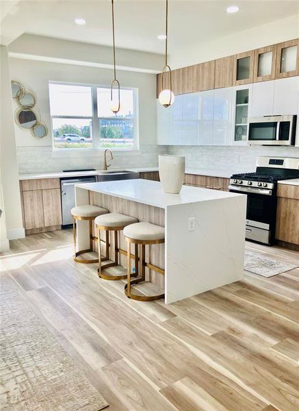 Modern kitchen featuring an elegant central island with seating and designer pendant lighting.