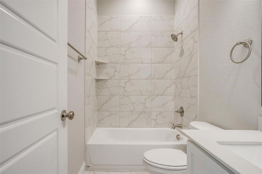 Full bathroom with vanity, tiled shower / bath combo, toilet, and tile patterned floors