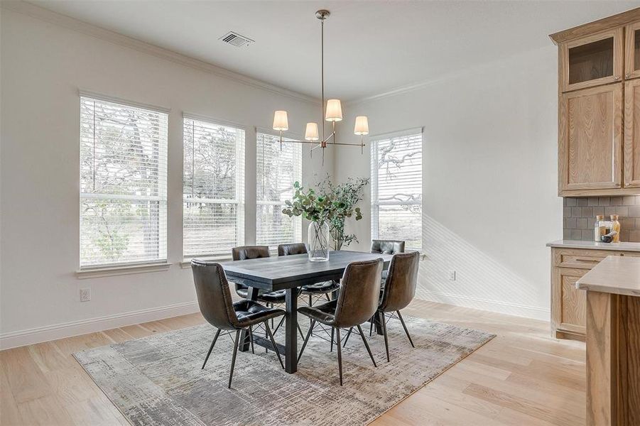 Dining space featuring light hardwood flooring, decorative chandelier and many windows for natural lighting