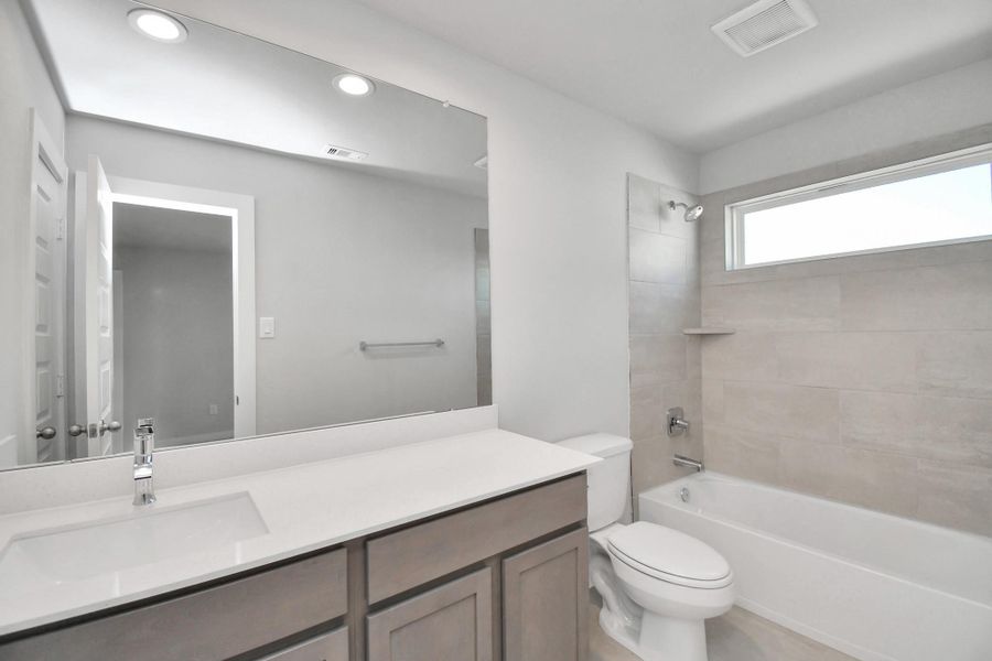 Secondary bath features tile flooring, bath/shower combo with tile surround, light stained wood cabinets, beautiful light countertop. Sample photo of completed home with similar floor plan. Actual colors and selections may vary. Secondary bath features tile flooring, bath/shower combo with tile surround, light stained wood cabinets, beautiful light countertop. Sample photo of completed home with similar floor plan. Actual colors and selections may vary.
