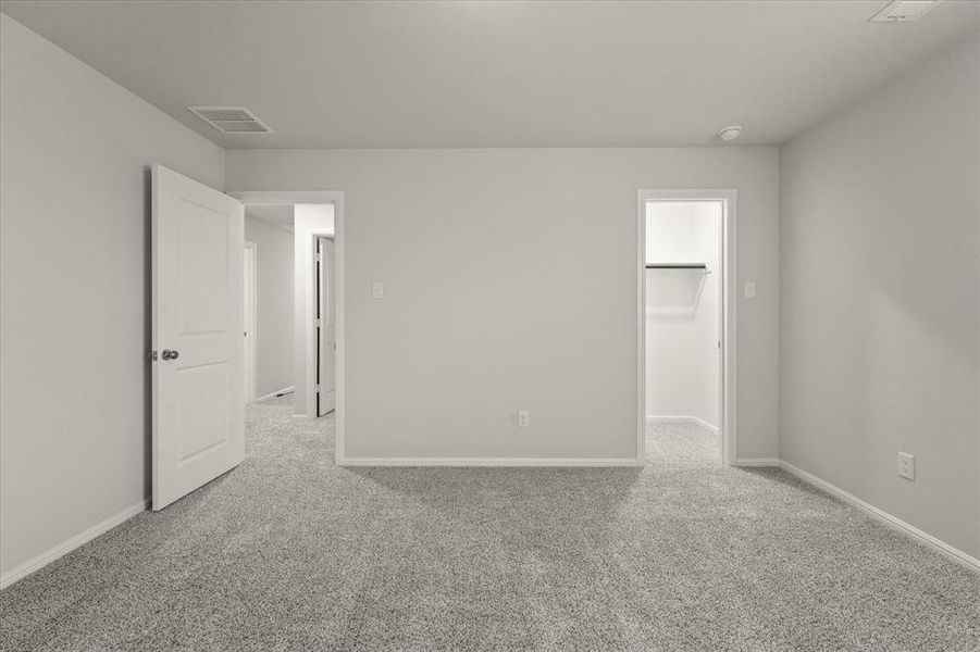 Unfurnished bedroom with a closet, a walk in closet, and light colored carpet