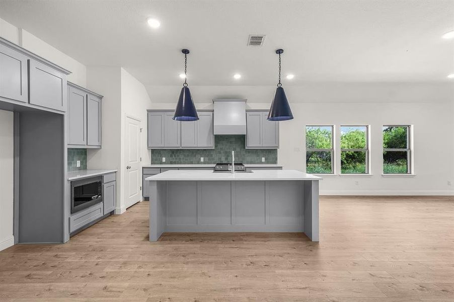 Kitchen featuring gray cabinets, backsplash, a breakfast bar, light floors, and recessed lighting