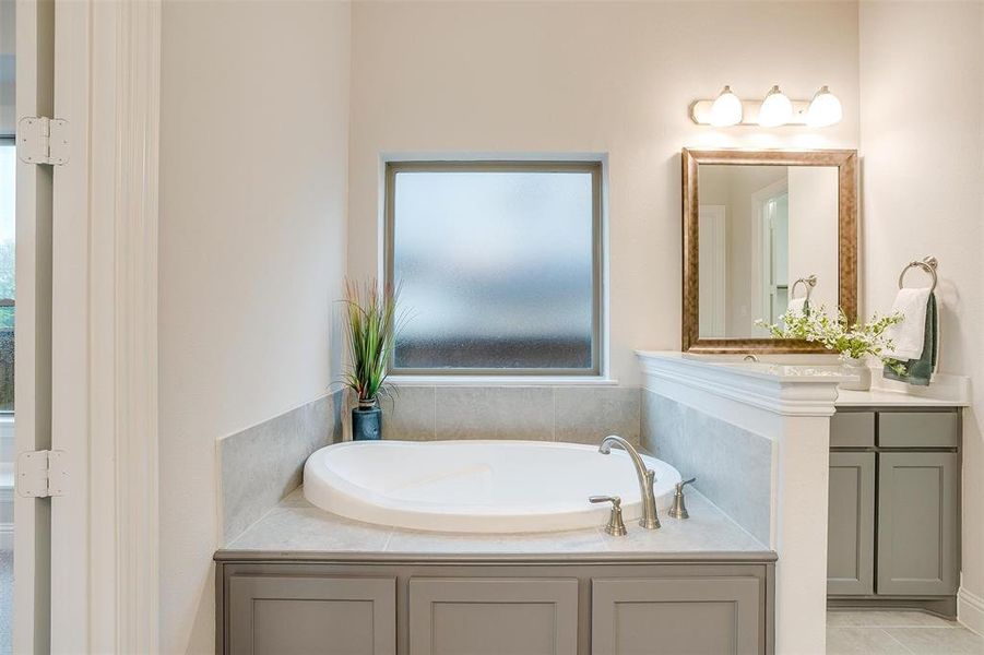 Bathroom with a bath, vanity, and tile patterned floors