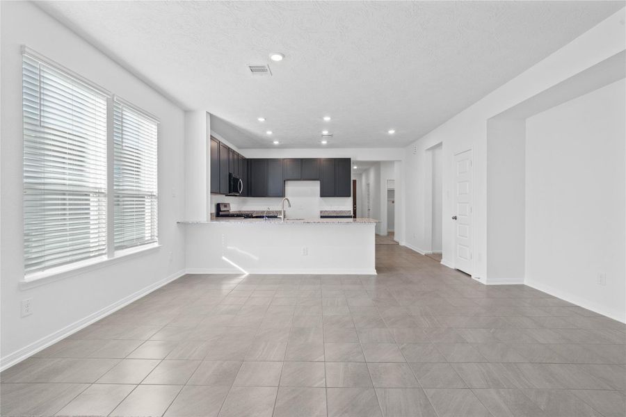 Create lasting memories around the table with family and friends in this inviting dining room! It showcases high ceilings, large windows with privacy blinds, tile flooring, and recessed lighting for a warm and welcoming atmosphere.